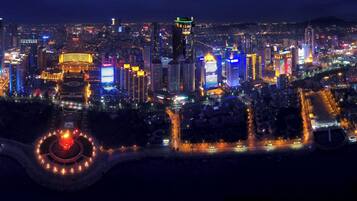 Un paisaje urbano nocturno con edificios iluminados y una plaza circular con luces.