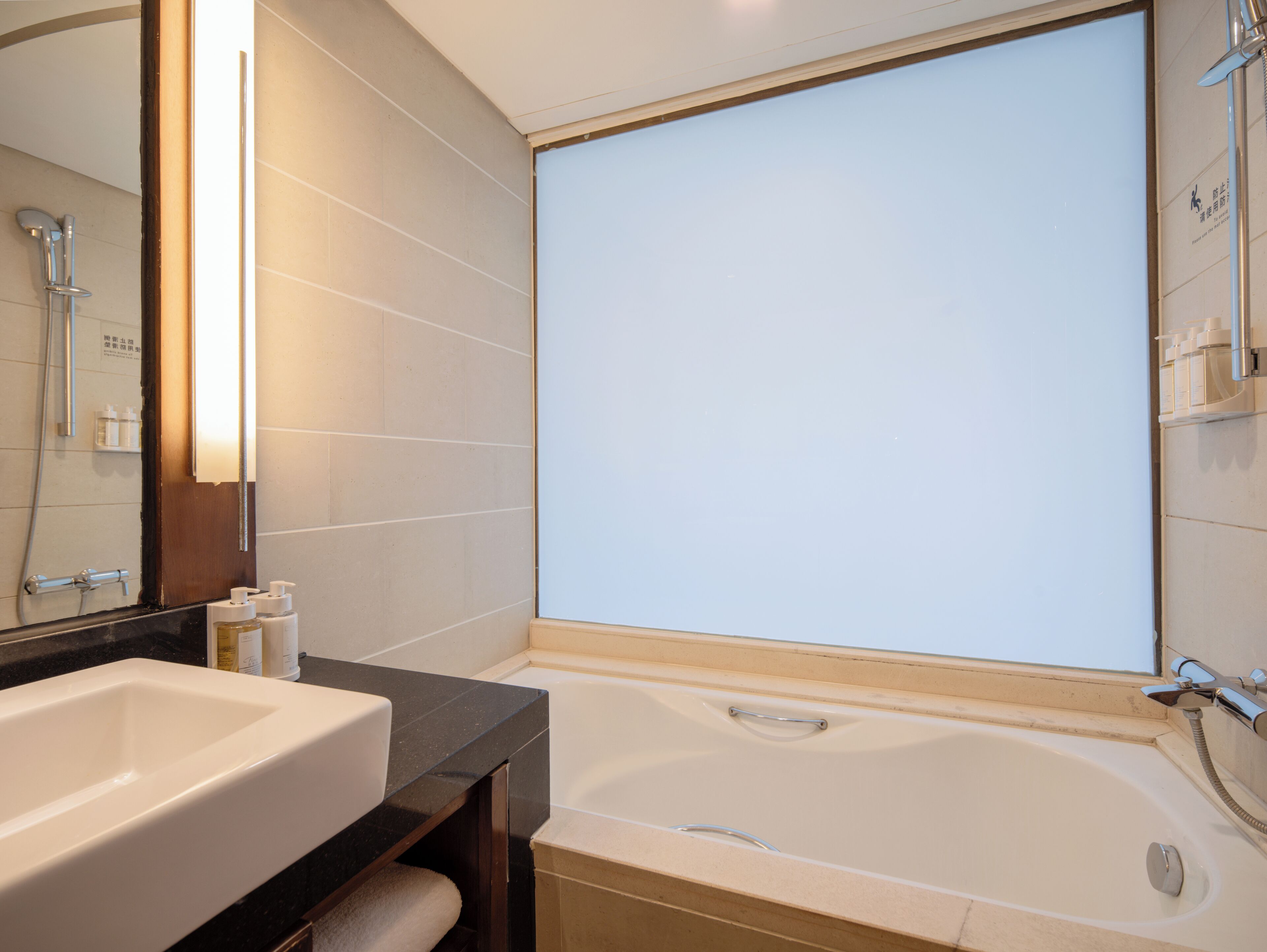 A modern bathroom with a bathtub, a large mirror, and a sink.