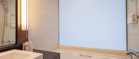 A modern bathroom with a bathtub, a large mirror, and a sink.