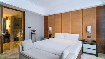 Quarto de hotel com uma cama grande, mesas de cabeceira, um espelho e área de chuveiro.