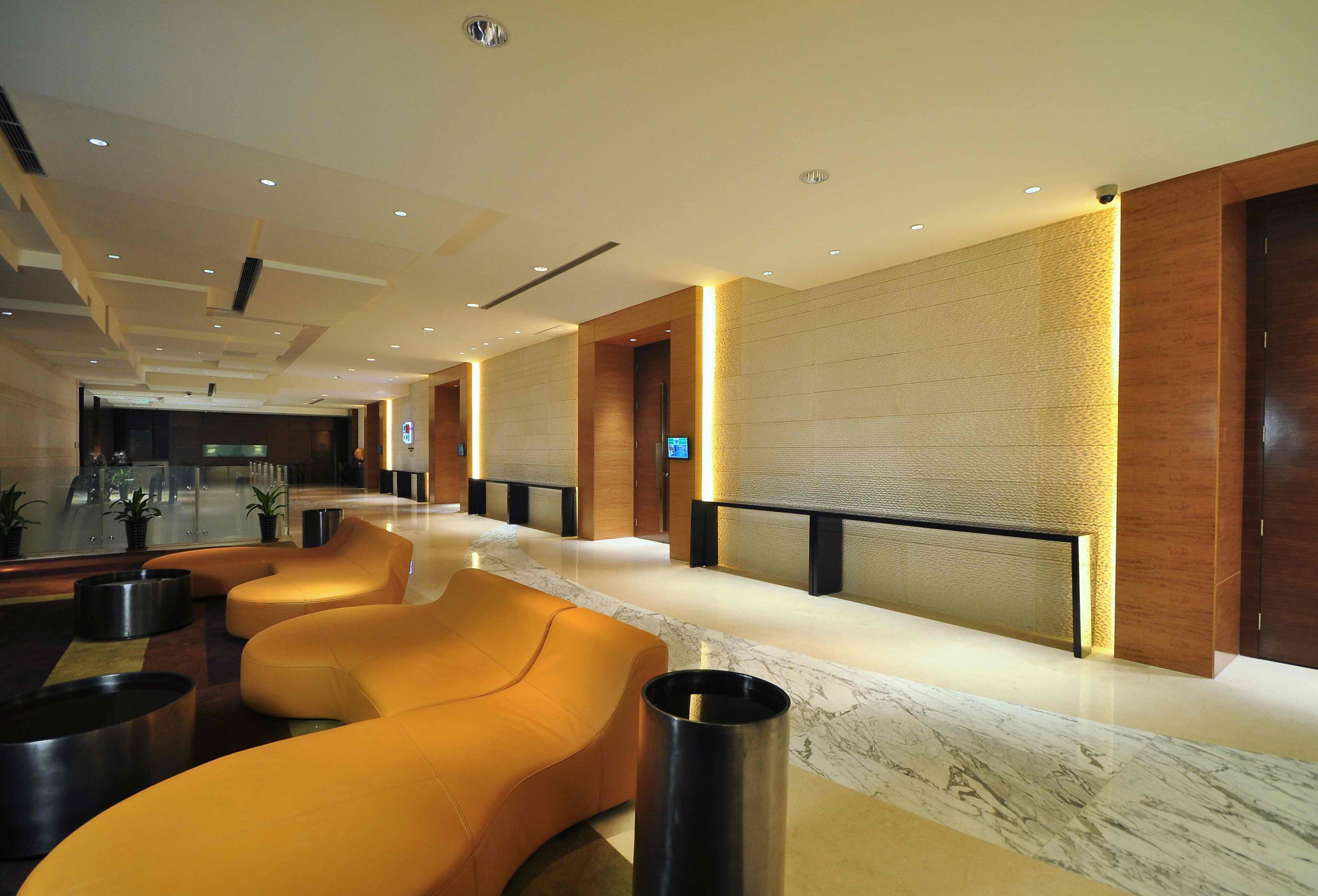 A modern lobby with seating areas, a reception desk, and a large screen.