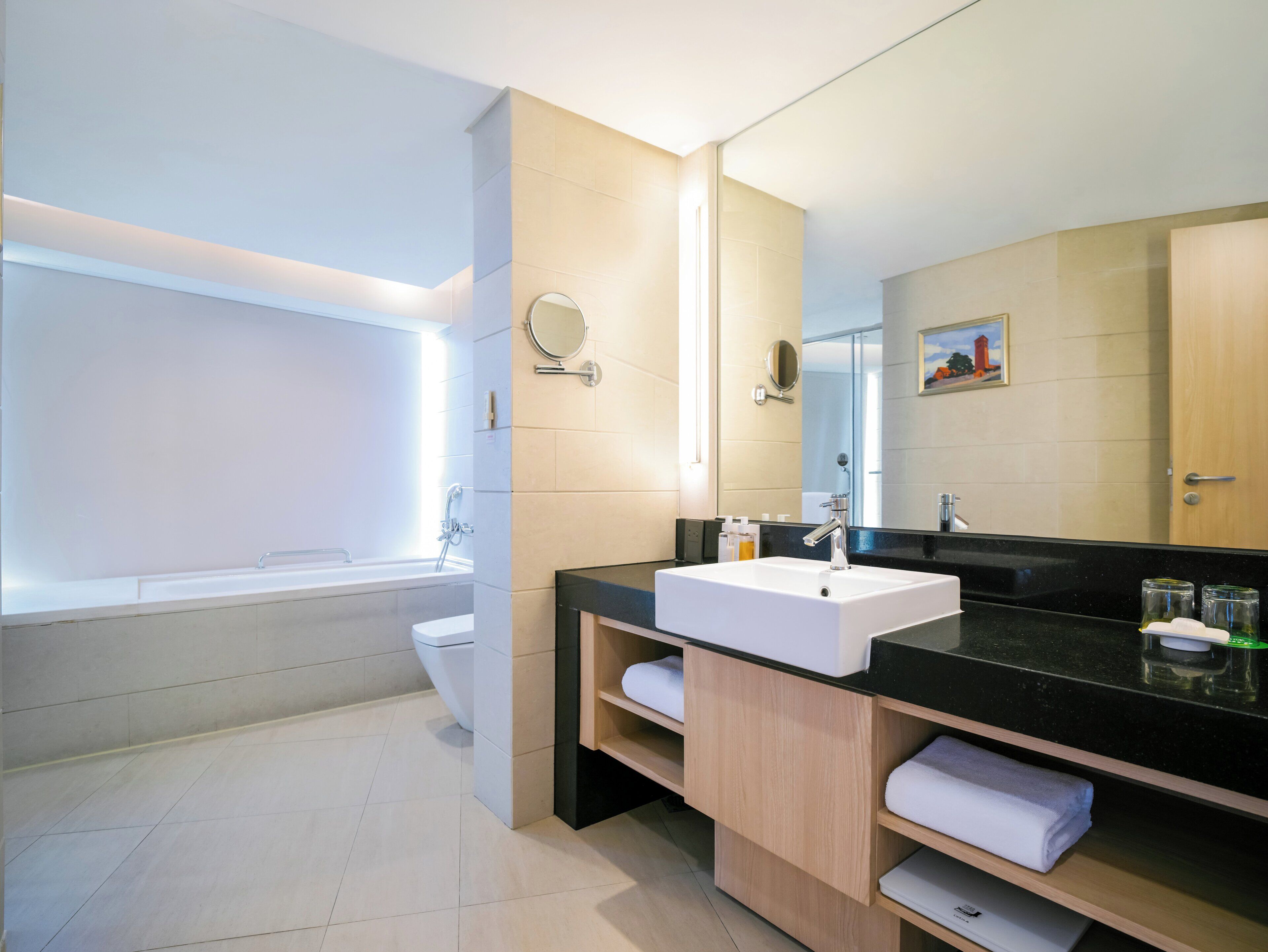 A modern bathroom with a bathtub, a sink, a mirror, and a toilet.