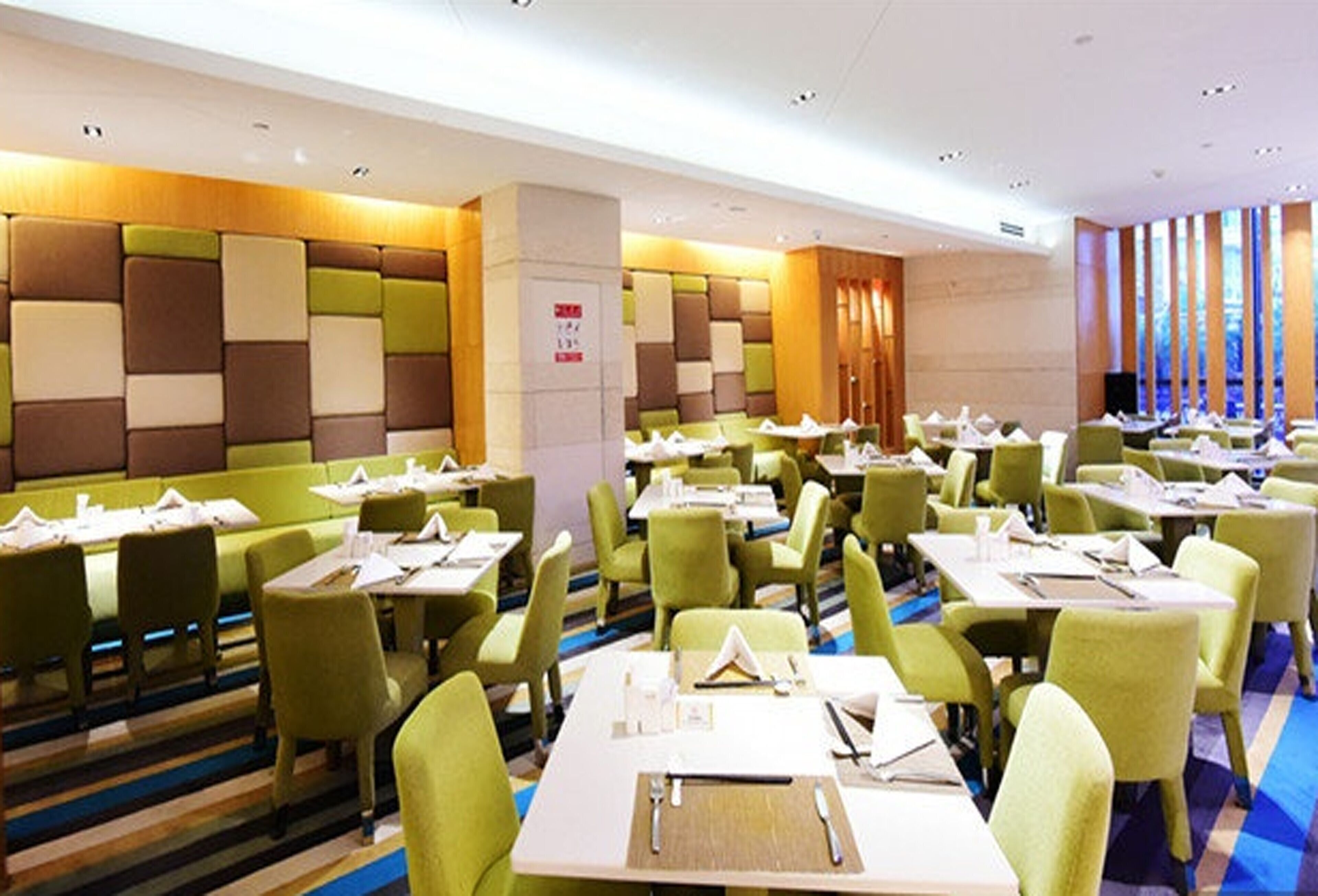 A hotel dining area with green booths and tables, each with a place setting.
