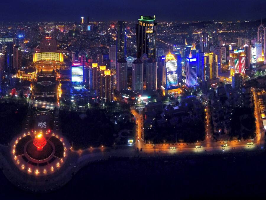 A cityscape at night with illuminated buildings and a circular park area.