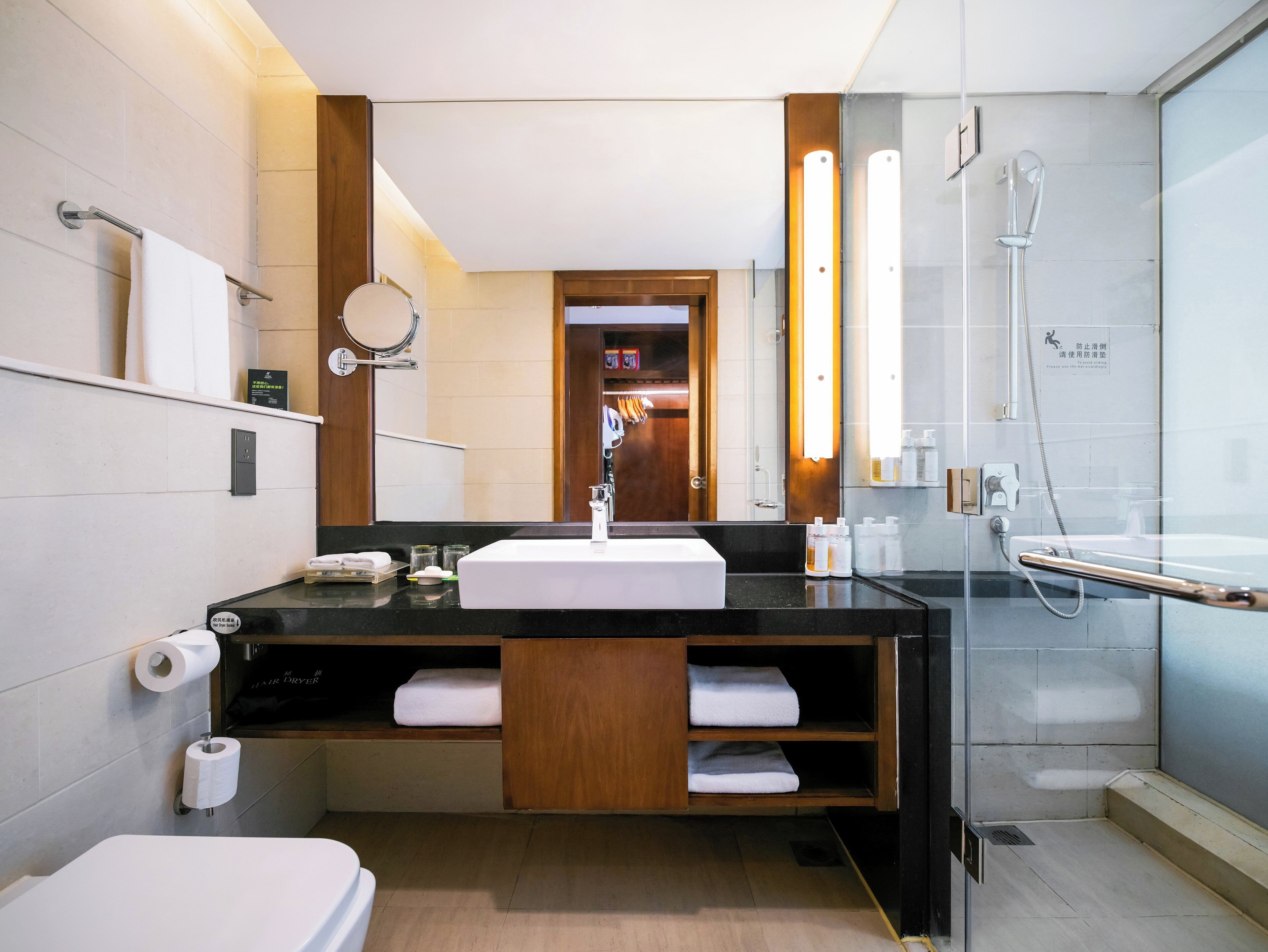 A modern bathroom with a white sink, a mirror, a towel rack, a shower, and a toilet.
