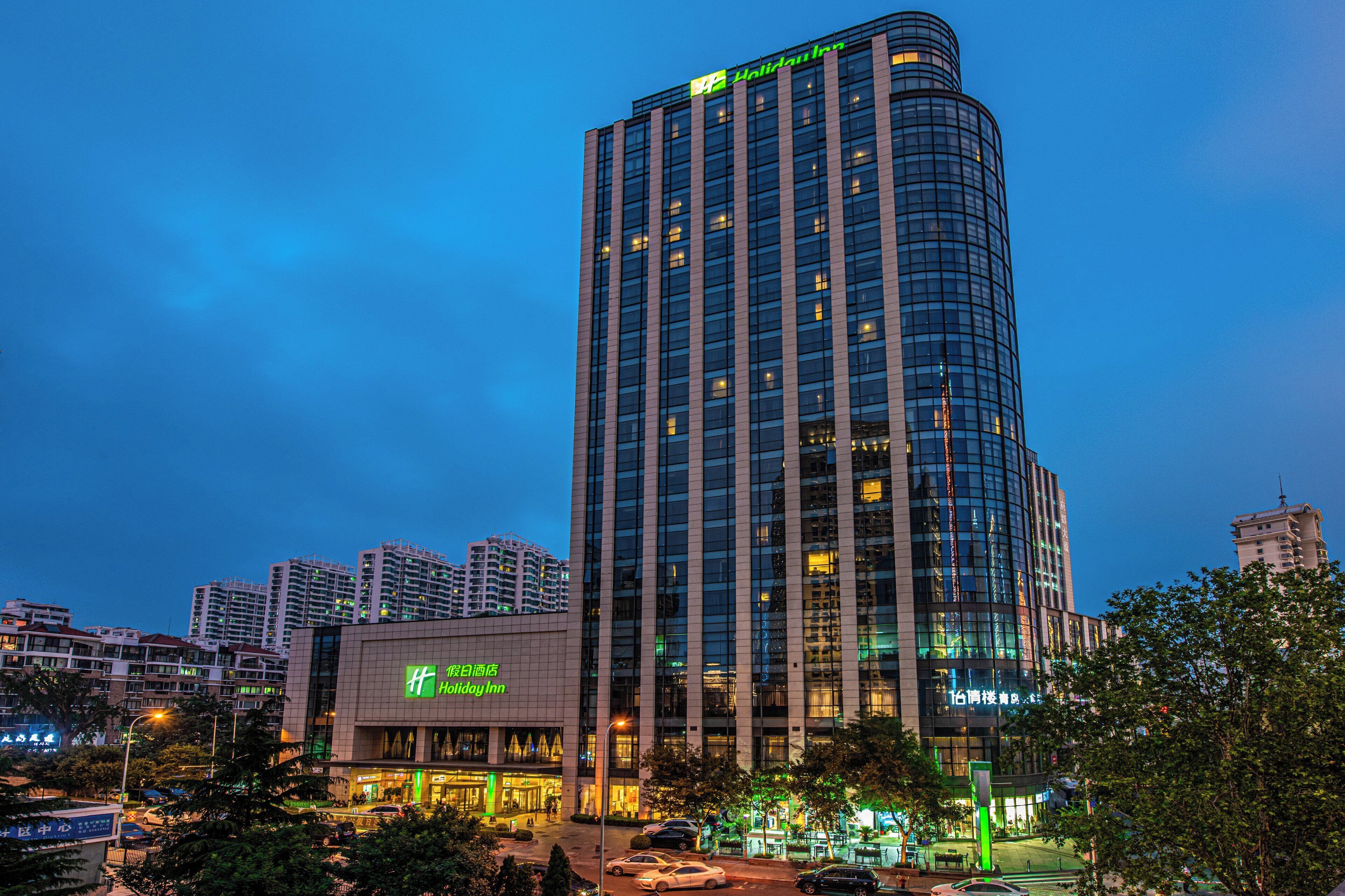 A high-rise hotel with a prominent Holiday Inn sign, surrounded by other buildings and trees.