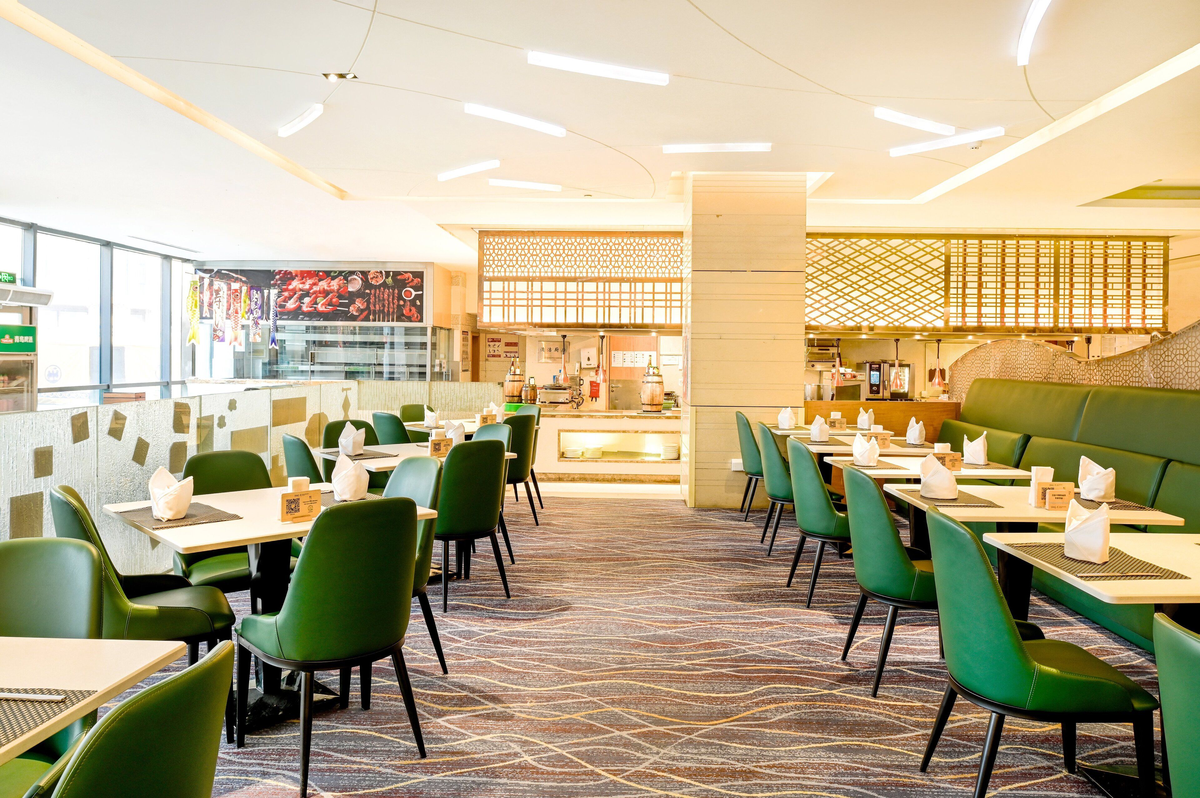 A modern restaurant with green seating, a patterned carpet, and a central counter.