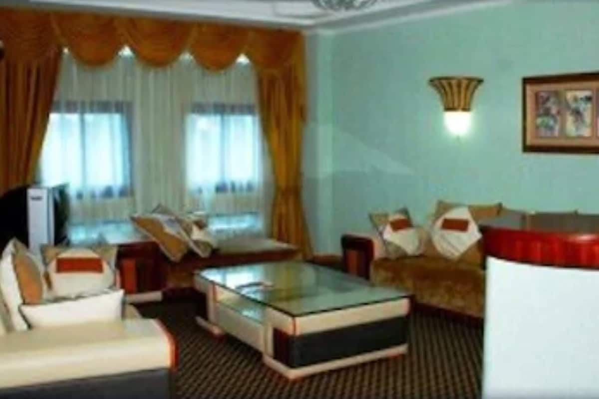 Una habitación de hotel con una cama, un sofá, una mesita de café y un televisor.