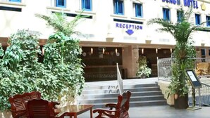 A hotel reception area with a staircase leading to the entrance, surrounded by potted plants and outdoor seating. - Imperial Botanical Beach Hotel (Entebbe)