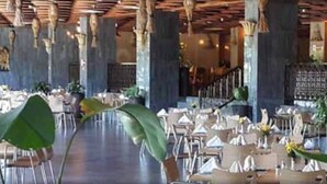 A spacious restaurant with high ceilings and exposed wooden beams. Tables are set with white tablecloths and centerpieces. - Imperial Botanical Beach Hotel (Entebbe)