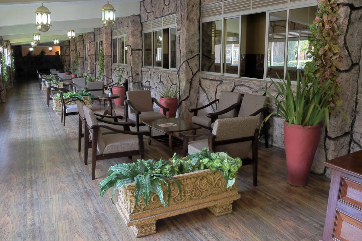 Un vestíbulo de hotel con paredes de piedra, muebles de madera y plantas en macetas.