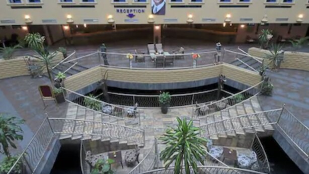 A multi-level atrium with a reception area, multiple staircases, and potted plants. - Imperial Botanical Beach Hotel (Entebbe)