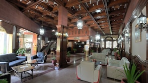 A lobby with wooden ceiling beams, a reception desk, and seating areas with potted plants. - Imperial Botanical Beach Hotel (Entebbe)
