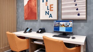 Ein Hotelrezeptionstresen mit Computer, Telefon und gerahmten Bildern.