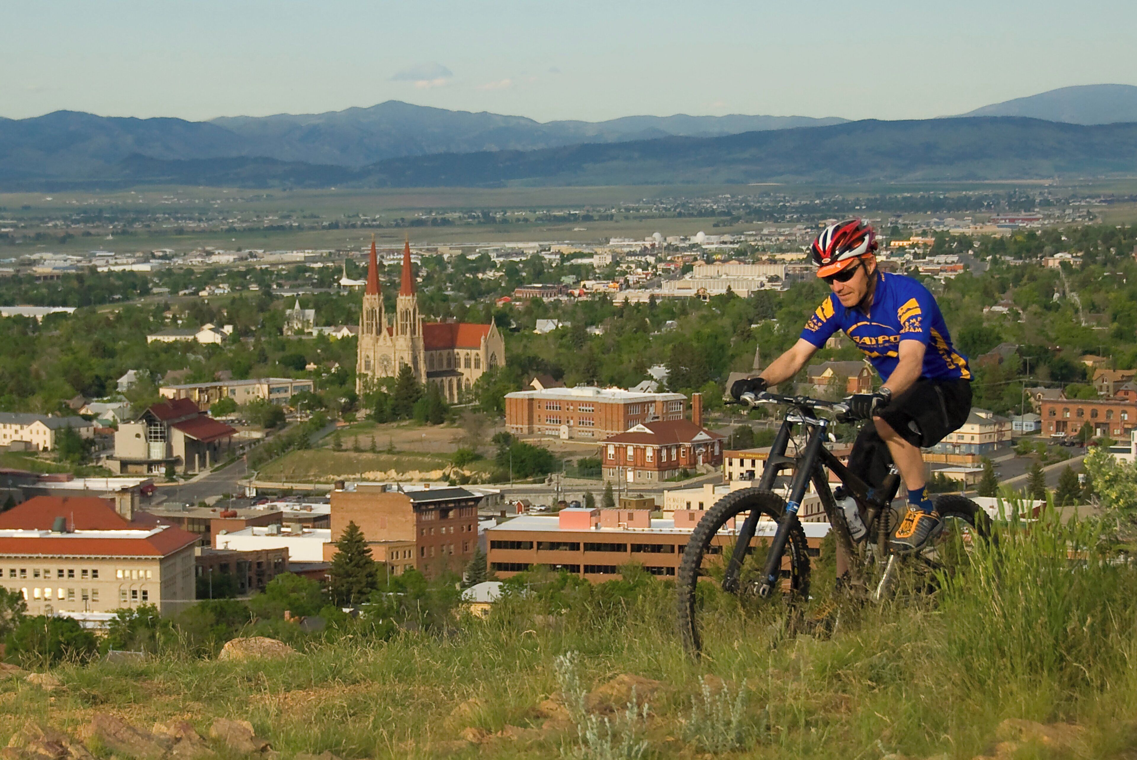 A cyclist on a mountain bike with a cityscape in the background.