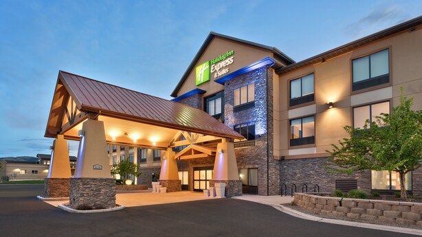 Ein Holiday Inn Express & Suites Gebäude mit überdachter Einfahrt, Steinsäulen und einer gut beleuchteten Fassade.