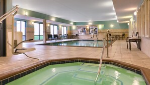 Ein Innenpool mit grünlichem Schimmer, umgeben von gefliesten Wänden und einer Sitzecke mit Stühlen und Tischen.