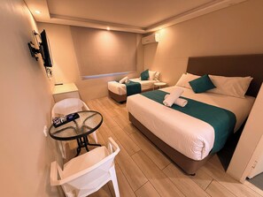 A hotel room with a bed, a chair, a small table, and a wall-mounted TV. - Marco Polo Motor Inn Sydney (Summer Hill)