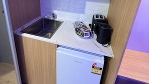 A compact kitchen with a microwave, sink, and a small refrigerator.