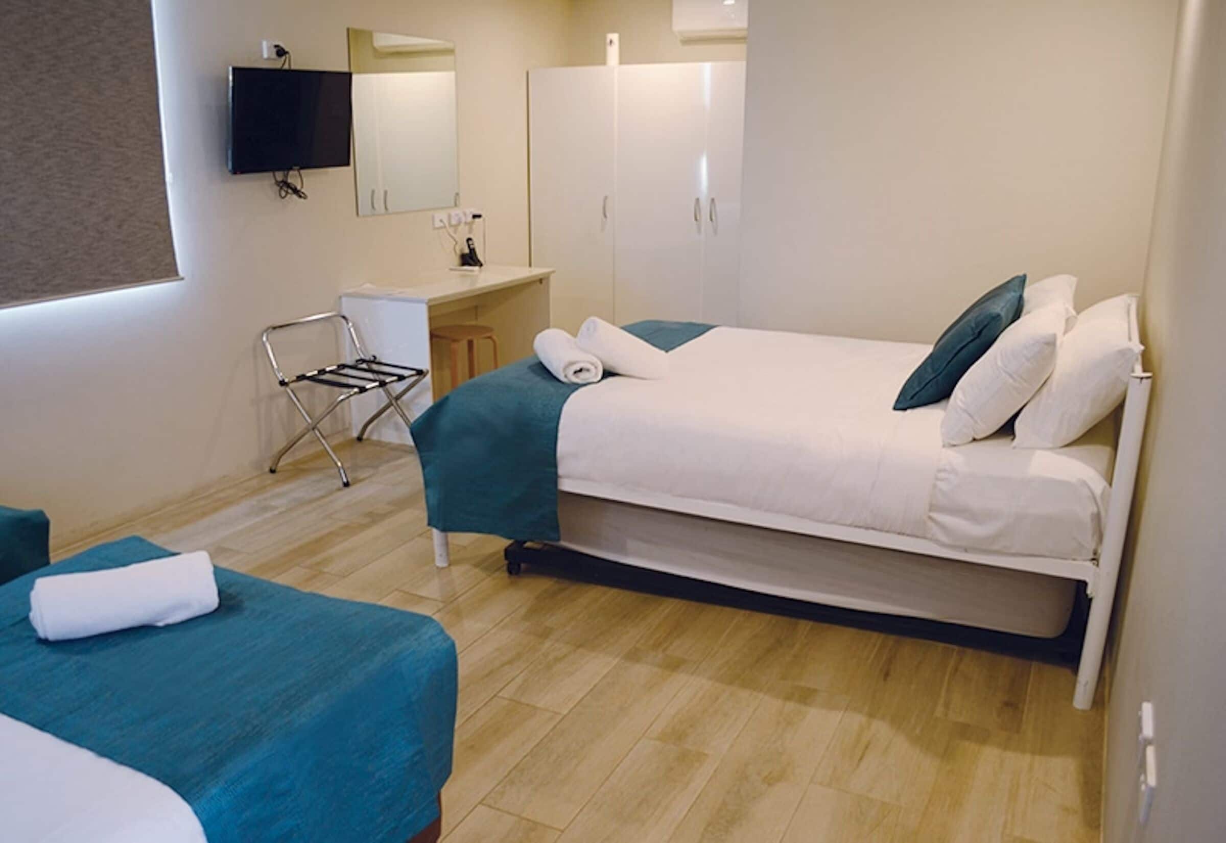 Habitación de hotel con una cama individual, un escritorio, una silla y un televisor montado en la pared.