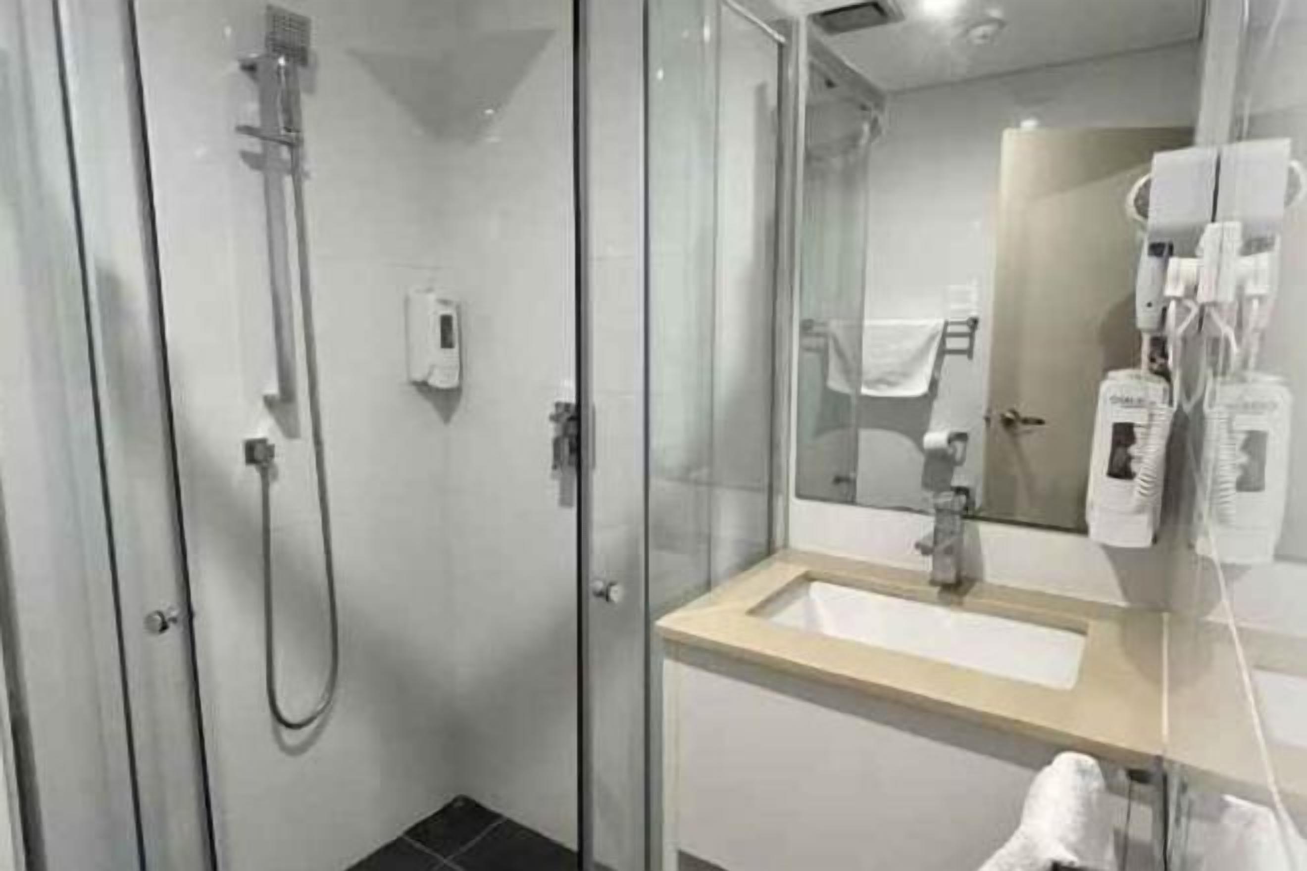 Badkamer | Een douche, een haardroger, pantoffels, handdoeken