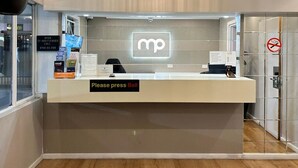 A reception desk with a 'Please press Bell' sign, a 'No Smoking' sign, and a 'Free Wi-Fi' sign.