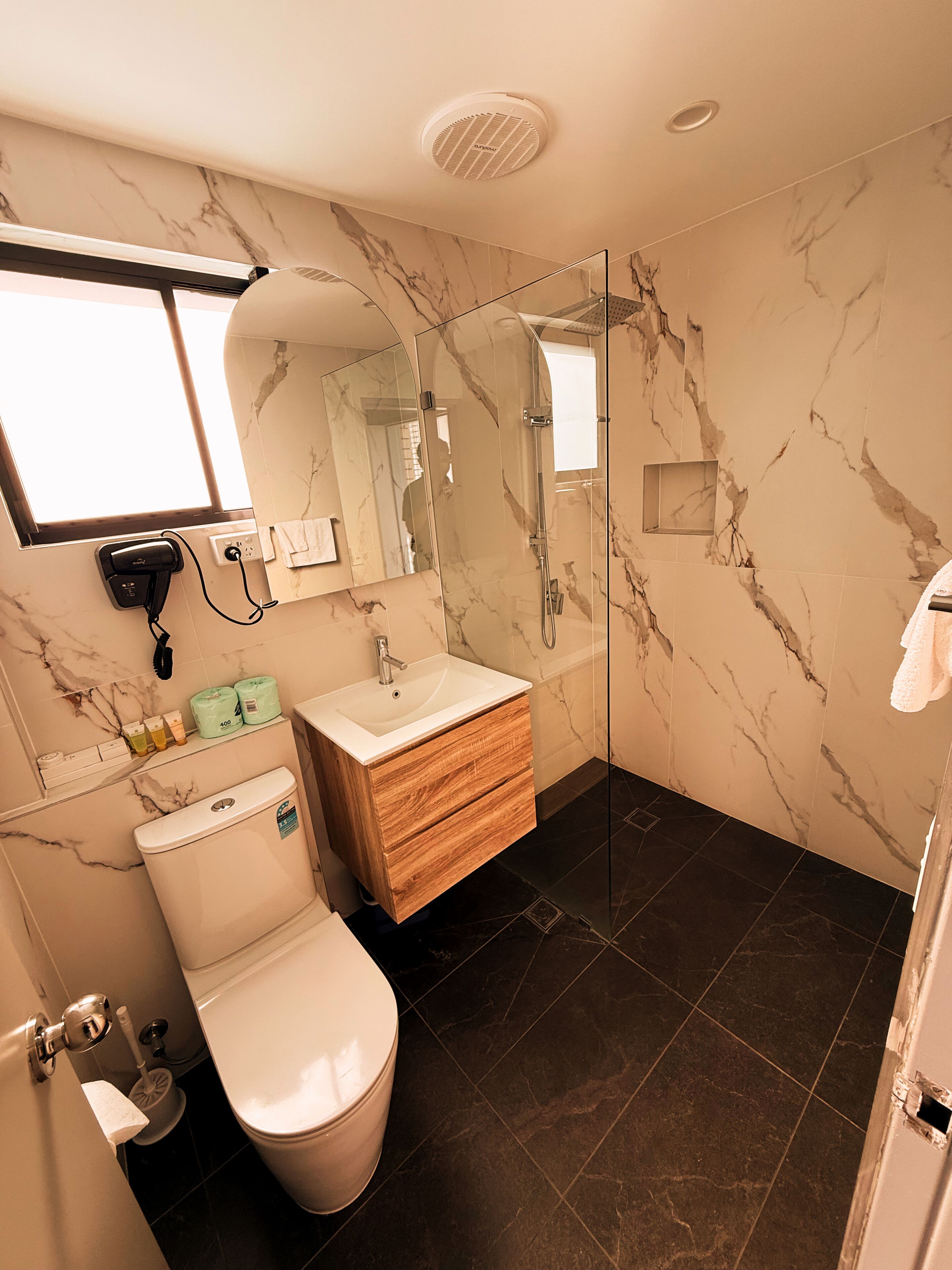 Un baño moderno con tocador de mármol, cabina de ducha de vidrio y un inodoro.