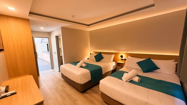 A hotel room with two beds, a desk, and a wooden panel wall.