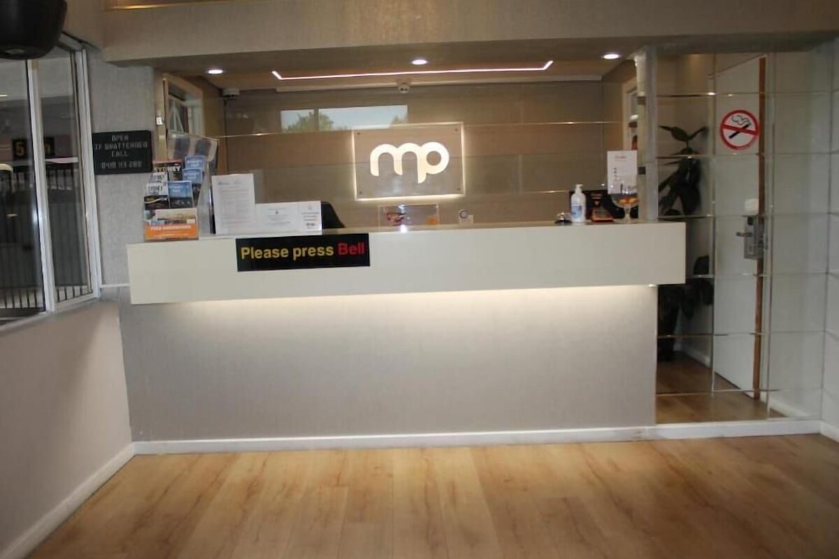 A reception desk with a logo, a sign that says 'Please press call,' and a no-smoking sign.