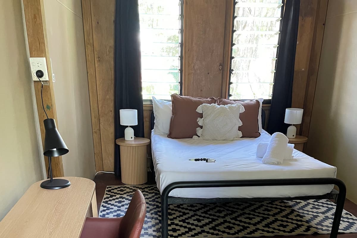 A bedroom with a bed, bedside tables, a desk, and a chair.