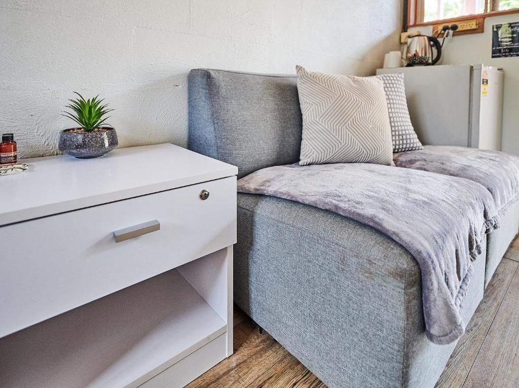 A modern room with a grey sofa, a white desk, and a small potted plant.