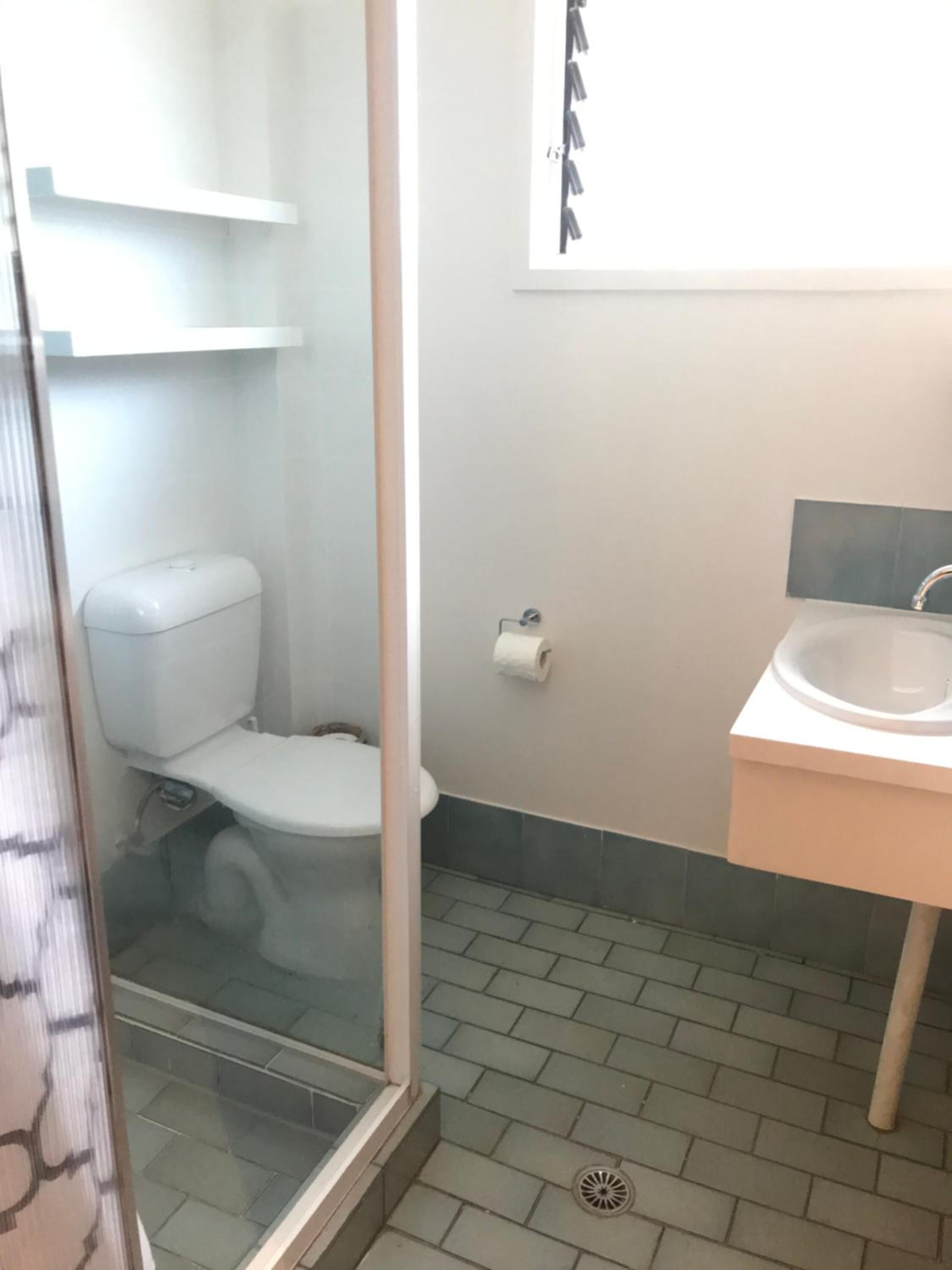 Et badeværelse med toilet, vask og bruseniche.