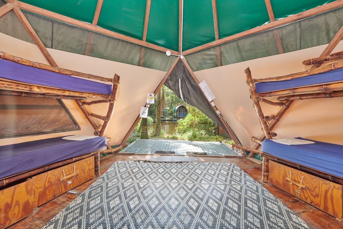 A tent with two beds, a patterned mat, and a view of greenery outside.