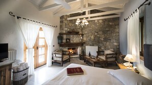 Una habitación acogedora con chimenea, una cama, un escritorio y un televisor.