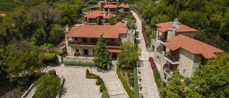 A hillside property with multiple stone buildings, terraced gardens, and a central courtyard.