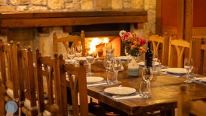 Mesa de comedor dispuesta para seis personas, con sillas, un florero y una botella de vino.