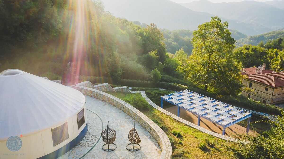 A yurt with a circular roof, a covered outdoor seating area, and a stone pathway.