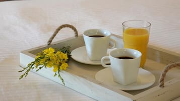A tray with two cups of coffee and a glass of orange juice, accompanied by a small bouquet of yellow flowers.