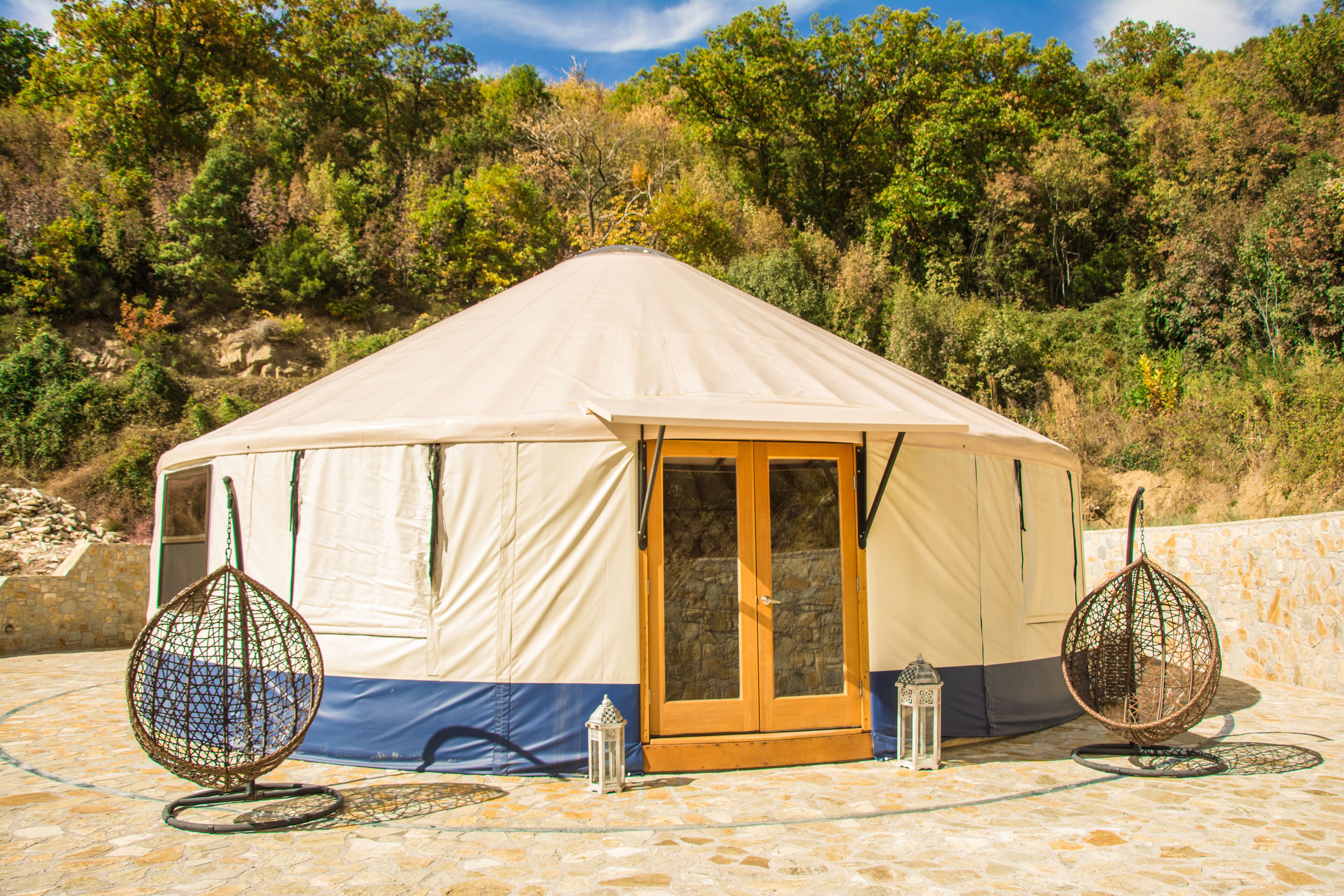 A large, beige tent with a wooden door and two hanging chairs.