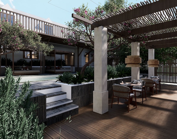 A covered outdoor seating area with steps leading to a pool, surrounded by greenery and a pergola.