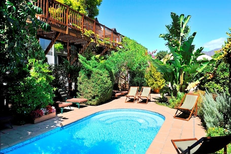 Una piscina al aire libre de temporada, sombrillas