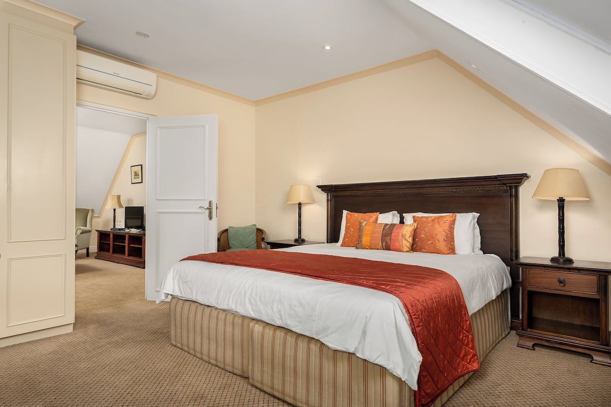 A hotel room with a large bed, two bedside tables with lamps, a wardrobe, and a television.