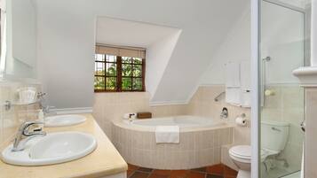 A modern bathroom with two sinks, a bathtub, and a toilet.