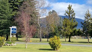 A sign for 'Parklands Apartments' with a view of a mountain and trees in the background. - Parklands Motel (Te Anau)
