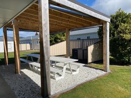 A covered outdoor area with picnic tables and a barbecue grill.
