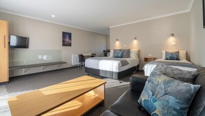 A modern hotel room with a bed, a desk, a sofa, and a TV. - Parklands Motel (Te Anau)