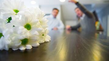A close-up of white flowers on a table with a blurred background of two people.