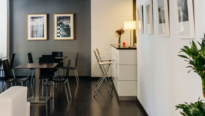 Een moderne kantoorruimte met een lange gang, een receptiegedeelte met een bureau en stoelen, ingelijste foto's aan de muur en een potplant.