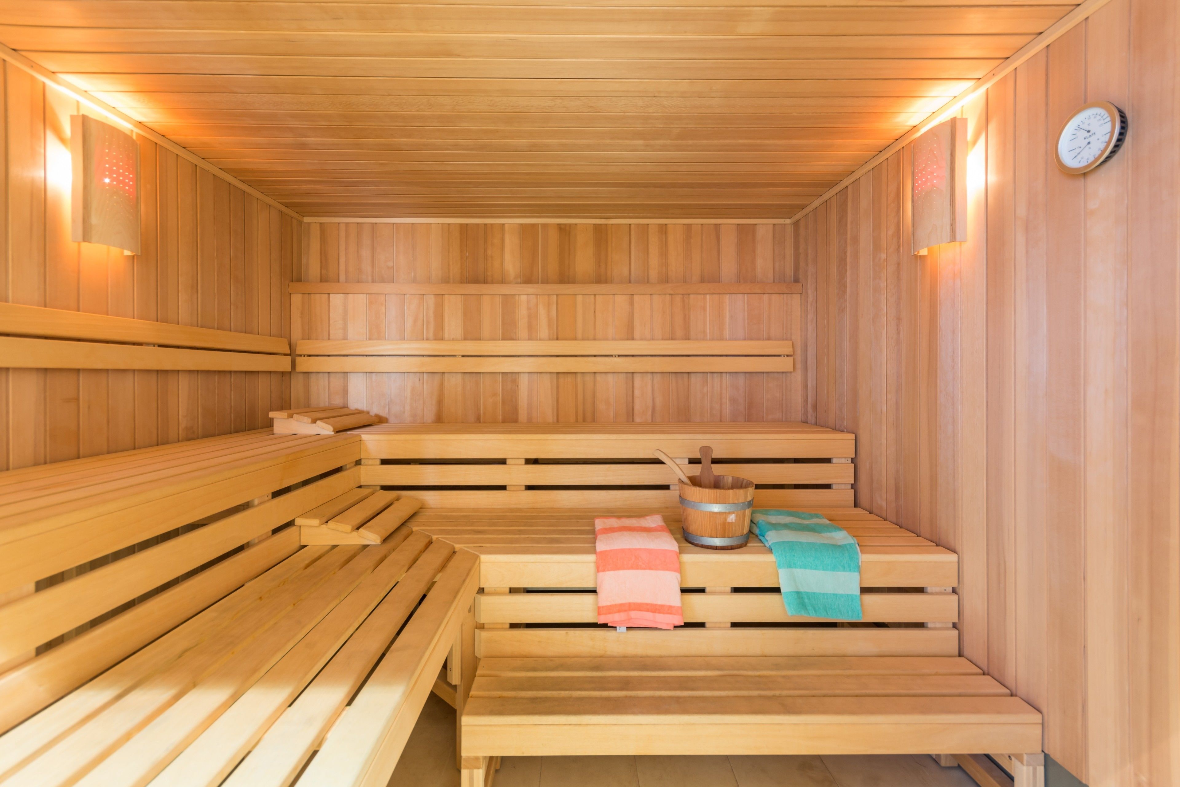 Eine Sauna mit Holzbänken, einem Eimer und einem Handtuch.