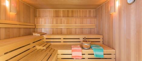Una sauna con bancos de madera, un balde y una toalla.